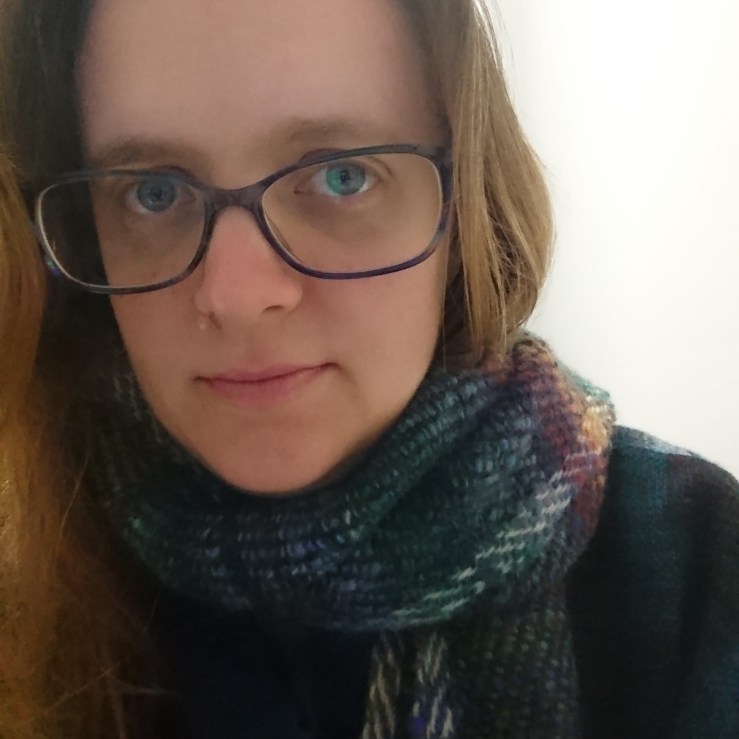 Profile image - Emily
A close-up view of a woman with light skin, blue eyes and brown hair wearing glasses and a multi-coloured scarf