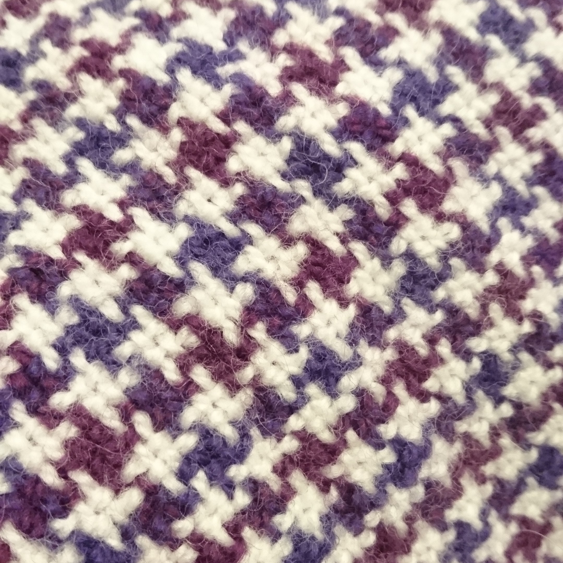 Weaving featuring small checked / criss-crosses of white, plum and purple in a houndstooth pattern.