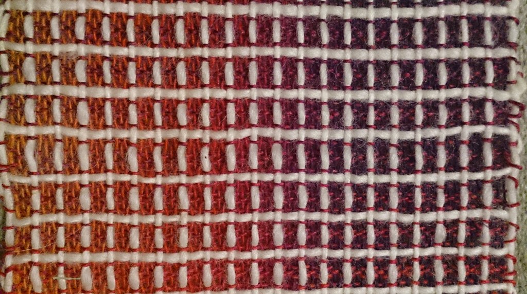 close up of weaving in a window-pane pattern in red, orange, purple and white